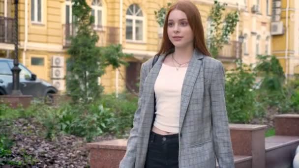 Kendine güvenen genç kadın şehrin arka bina sarı sokakta yürürken ceketli zencefil — Stok video