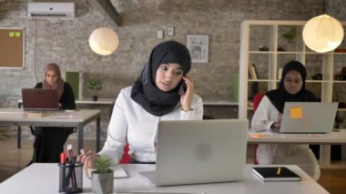 Üç genç Müslüman kadın oturuyor ve modern ofis, Evet, güzel Müslüman kadın çalışan hijab içinde gülümseyen