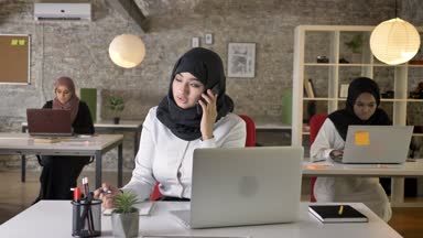 Üç genç Müslüman kadın içinde oturan ve laptop modern ofiste güzel bir Müslüman kadın, Evet yazarak hijab meşgul