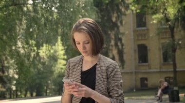 Genç tatlı kız ileti Smartphone cep telefonu ile parkta gündüz, yaz, iletişim kavramı yazmakta olduğunu