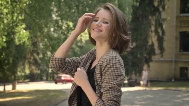 Jeune belle fille joue avec les cheveux dans le parc en journée en été, regarder à la caméra, concept flirt — Video