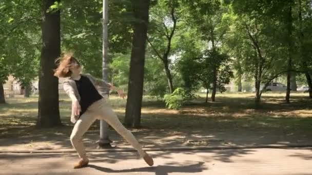 Jeune belle fille danse sur le chemin dans le parc en journée, en été, concept de mouvement, vue latérale, dolly shot — Video