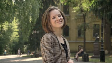 Genç güzel kız saç parkta gündüz yaz aylarında dokunuyor gülümseyerek, kameraya izlerken