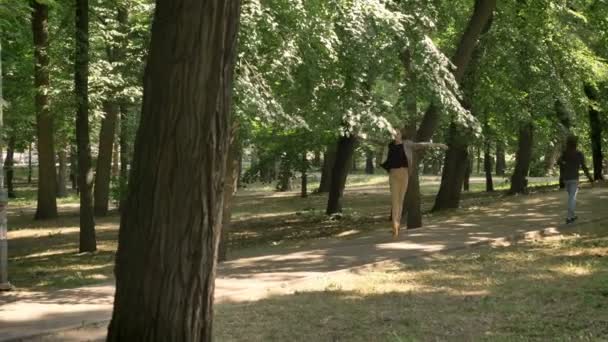 Молода красива дівчина танцюрист стрибає в парку вдень, влітку, концепція руху, ляльковий постріл — стокове відео