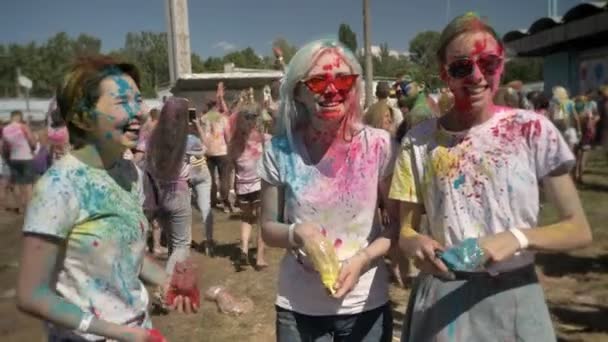 Trzy młode dziewczyny wieloetnicznego rzucają kolorowy proszek na festiwalu holi w dzień w lecie, śmiejąc się, pojęcie przyjaźni, kolor koncepcja — Wideo stockowe