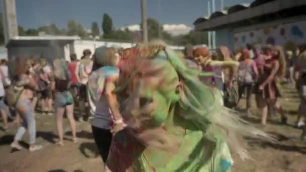 Young happy girl in colourful powder is jumping and shaking head on holi festival in daytime in summer, color concept — Stock Video