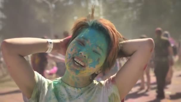 Jovem menina asiática feliz está brincando com o cabelo com pó colorido no festival holi durante o dia no verão, conceito de cor — Vídeo de Stock
