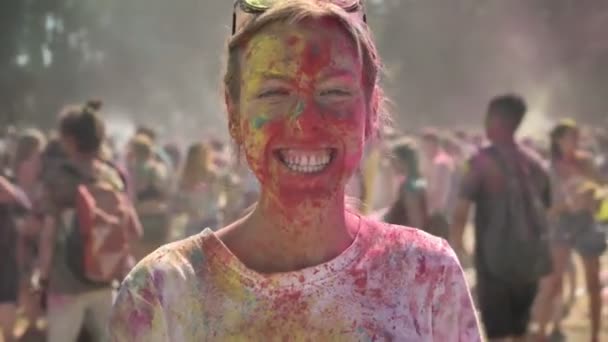 Lycklig flicka i färgglada pulver dansar på holi festivalen dagtid på sommaren titta på kameran, färg koncept, känslomässiga koncept — Stockvideo