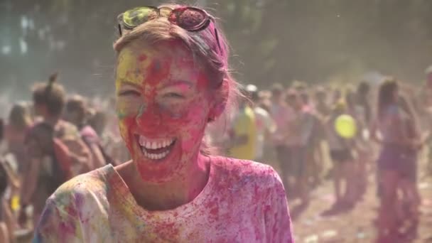 Young happy girl in colourful powder is histerically laughing and dancing on holi festival in daytime in summer, watching at camera, color concept, emotional concept — Stock Video