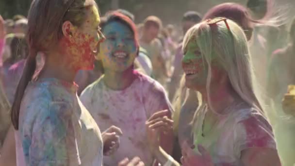 Три молоді щасливі багатоетнічні подружки танцюють і посміхаються на фестивалі холі вдень влітку, концепція дружби, концепція свята — стокове відео