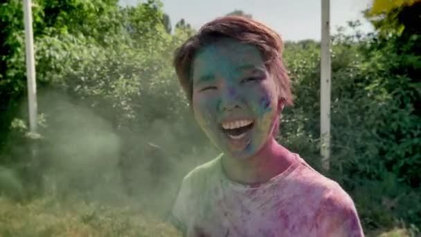 Jonge cheerfyl Aziatisch meisje in kleuren wordt gegooid met kleurrijke holi festival poeder overdag in de zomer kleur concept — Stockvideo