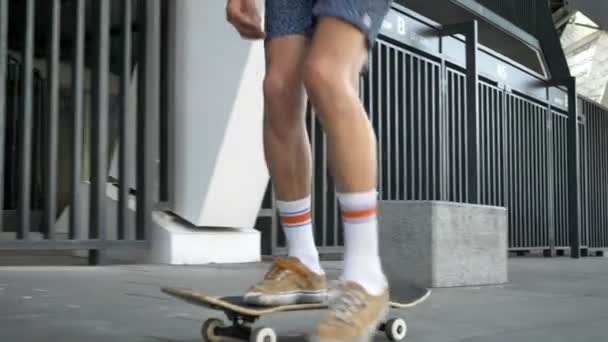 Piernas masculinas haciendo trucos, ollie en el monopatín, pies skateboarder mientras patina en la ciudad, vista desde el lado — Vídeo de stock