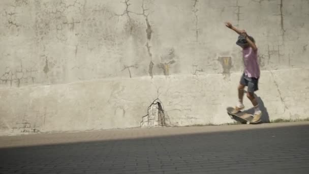 Стильный скейтбордист делает трюк на старой стене — стоковое видео