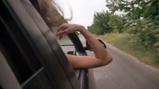 Giovane bella ragazza sognatore mette testa e mano fuori dal finestrino dell'auto durante la corsa, concetto trevel, concetto di sogno — Video Stock