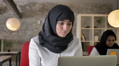 Genç Müslüman kadınların çalışma ve dizüstü bilgisayar, bir tanesi ofiste oturan iki kadın yazarak türban Tesettür Afrika kadın