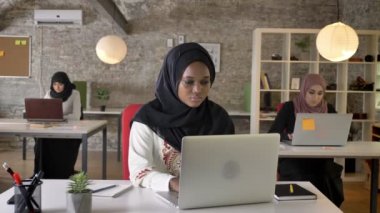 Dizüstü bilgisayarda yazarak ve öksürük, üç güzel Müslüman kadın çalışma modern office hijab genç Afrika Müslüman kadınları