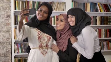 Üç genç Tesettür alarak selfie Kitaplığı ' nda Müslüman kadın arkadaşlar kendilerini mutlu ve gülümseyen fotoğrafını çekmek çekici