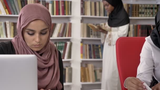 Três Jovens Mulheres Muçulmanas Hijab Estudando Biblioteca Leitura Escrita Prateleiras — Vídeo de Stock