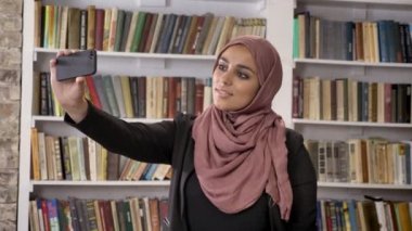 Genç Müslüman güzel kadınlar türban alarak selfie sonra telefon görünümlü ve Fotoğraf Kitaplığı ' nda izlerken gülümsüyor