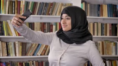 Genç Müslüman güzel kadınlar türban alarak selfie sonra telefon görünümlü ve telefon Kitaplığı ' nda fotoğrafları izlerken gülümsüyor