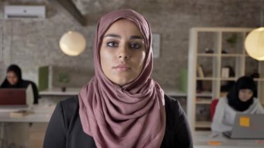 Kamera, ciddi ve ilgili seyir hijab genç Müslüman kadınların, üç modern ofis içinde laptop üzerinde çalışan kadın portre