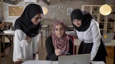 Üç genç Müslüman kadın ve gülümseyen içinde laptop işaret, Office iş planı söz proje tartışıyor hijab içinde