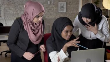 Meslektaşları ile modern ofis içinde laptop üzerinde proje hakkında konuşmak hijab genç siyahi Müslüman kadınları