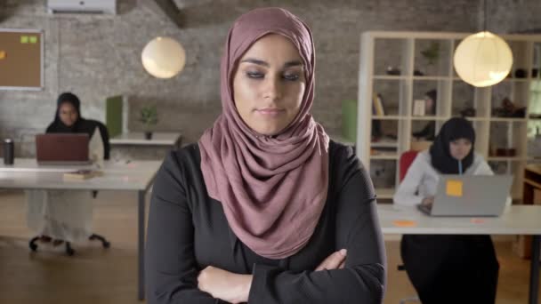 Молодые мусульманки в хиджабе со скрещенными руками, качающие головой в разногласиях, три женщины, работающие на ноутбуке в современном офисе — стоковое видео