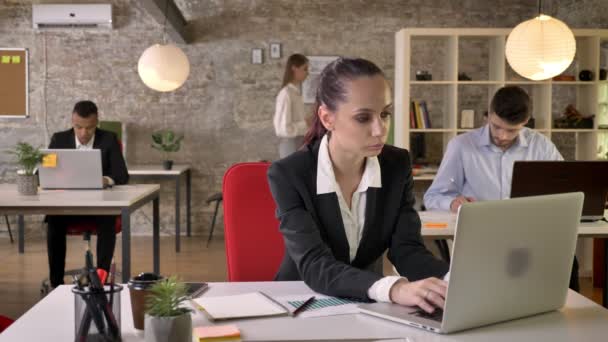 Junge schöne Geschäftsfrau schaut Laptop im Büro, schaut in die Kamera, lächelt, die Menschen vernetzen sich mit Technologien, Arbeitskonzept, Geschäftskonzept, Kommunikationskonzept, emotionale — Stockvideo
