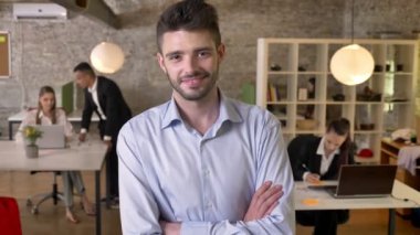 Genç işadamı, ofis, kamerada izliyor gülümseyerek, silah çarpı işareti vardır, arkadaşları ağ teknolojileri, çalışma kavramı, iş kavramı, arka plan bulanık