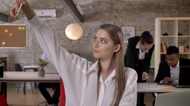 Genç çekici işkadını Smartphone cep telefonu ile Office selfie yapıyor, iş arkadaşları ağ teknolojileri, çalışma kavramı, iş kavramı, iletişim kavramı ile