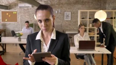 Genç ciddi işkadını tablet ofis, kameraya, izlerken gülümsüyor, iş arkadaşları ağ teknolojileri, çalışma kavramı, iş kavramı, iletişim kavramı ile dokunarak