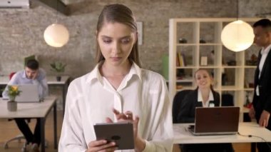 Konsantre genç işkadını dokunarak tablet ofis, izlerken kameraya, iş arkadaşları ağ teknolojileri, çalışma kavramı, iş kavramı, iletişim kavramı ile.