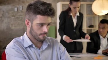 Konsantre genç işadamı kameraya, izlerken gülümsüyor, insanların ağ teknolojileri, çalışma kavramı, iş kavramı, iletişim kavramı, arka plan bulanık ile iş yerinde, biri