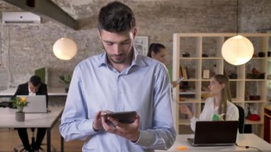 Genç işadamı Internet Tablet ofis, izlerken kameraya, arkadaşları ağ teknolojileri, çalışma kavramı, iş kavramı, iletişim kavramı ile sörf yapıyor.