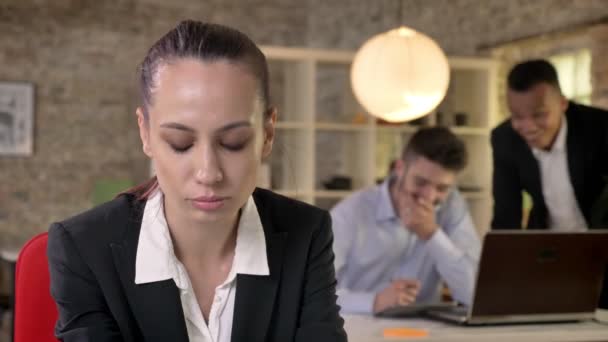 Молодая красивая деловая женщина расстроена из-за своих коллег-мужчин на заднем плане сплетни о Херм, сексизм концепции, Bulling концепция — стоковое видео