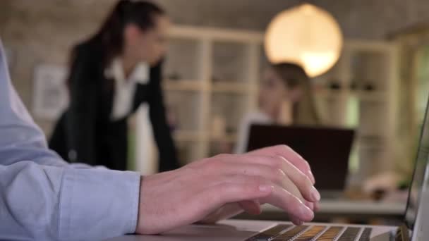 Homme d'affaires tape sur ordinateur portable dans le bureau, ses collègues sont en réseau avec les technologies, fond flou, concept de travail — Video