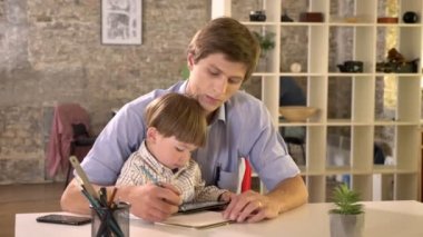 Oğlunun nasıl yazmak için öğretim, modern ofis masada oturan genç baba