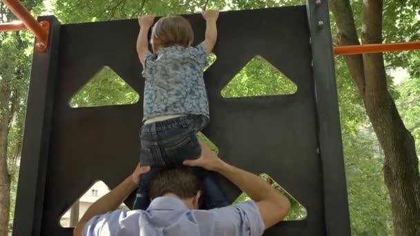 Unga far att placera hans lille son på hans hals och hoppning i park med pinjeträd, summertime — Stockvideo