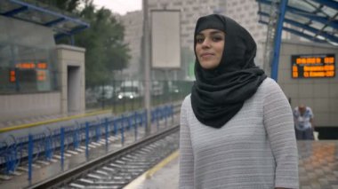 Hijab genç Müslüman kadın tren n Tren İstasyonu, yağmur, din kavramı, kentsel kavramı için bekliyor. Hava kavramı