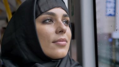Yüz hijab genç tatlı Müslüman kadının otobüs, taşıma kavramı, kentsel kavramı, hava kavram, kavram rüya yağmurlu penceresinde izliyor