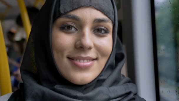 Jovem mulher muçulmana doce no hijab está assistindo a câmera no ônibus, conceito de transporte, conceito urbano, conceito de tempo, conceito de sonho — Vídeo de Stock