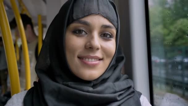 Νέοι όμορφη μουσουλμανική γυναίκα στο χιτζάμπ βλέποντας κάμερα στο λεωφορείο, μεταφοράς έννοια, αστικός κοίλος, έννοια καιρός, όνειρα έννοια — Αρχείο Βίντεο