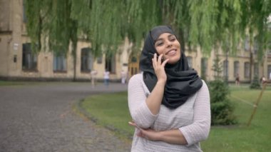 Hijab genç Müslüman kız telefonda konuşurken ve Bina arka plan, religiuos kavramı, iletişim kavramı mavi hava, gülümseyen