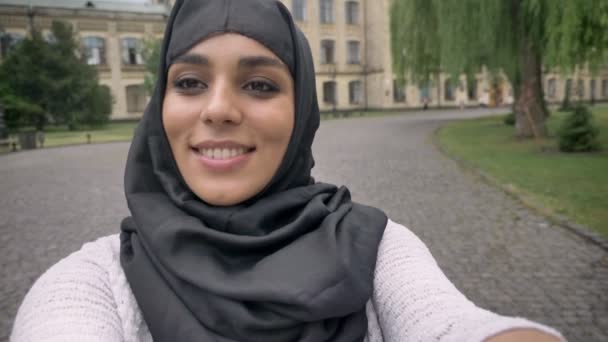 Jovem menina muçulmana feliz no hijab está fazendo vídeo em tempo azul, conceito de comunicação, conceito religioso, construindo em segundo plano — Vídeo de Stock