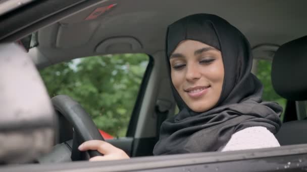 Nézi a kamera, a religiuos fogalma, a közlekedési koncepció autó, ül a vonzó fiatal muszlim lány hidzsáb — Stock videók