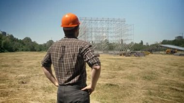 Kendine güvenen mimar arıyor metal konstrüksiyon ve saman alan üzerinde duran, arkadan görüntülemek
