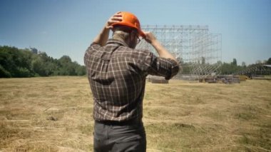 Kask saman sahada ayakta arka plan üzerinde metal konstrüksiyon bakarak emin Oluşturucusu arkası