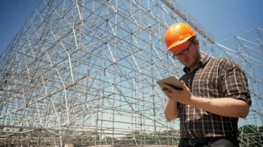 Tablet tutarak ve arka plan, papatyanın ve ciddi, planlama ve yeni proje tasarımı metal yükleme bakarak genç mimar
