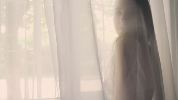 Silhouette fiatal szexi lány fehérnemű tüll mögött, és nézi a kamerát, játszik a haj, flirt koncepció — Stock videók